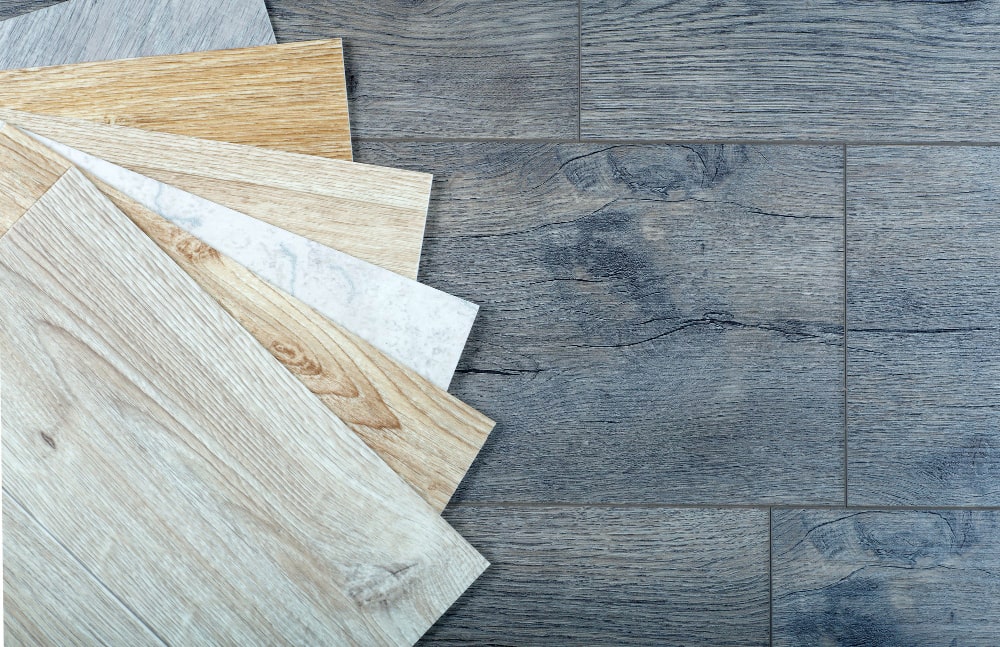 Wooden flooring samples in various colors on a wooden surface