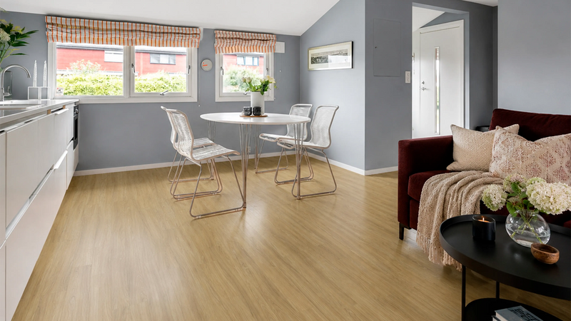 Spotted gum look vinyl plank flooring in a kitchen and dining area with a round table and white chairs