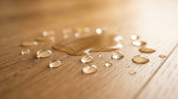 Water droplets beading on the water-resistant surface of oak hybrid flooring