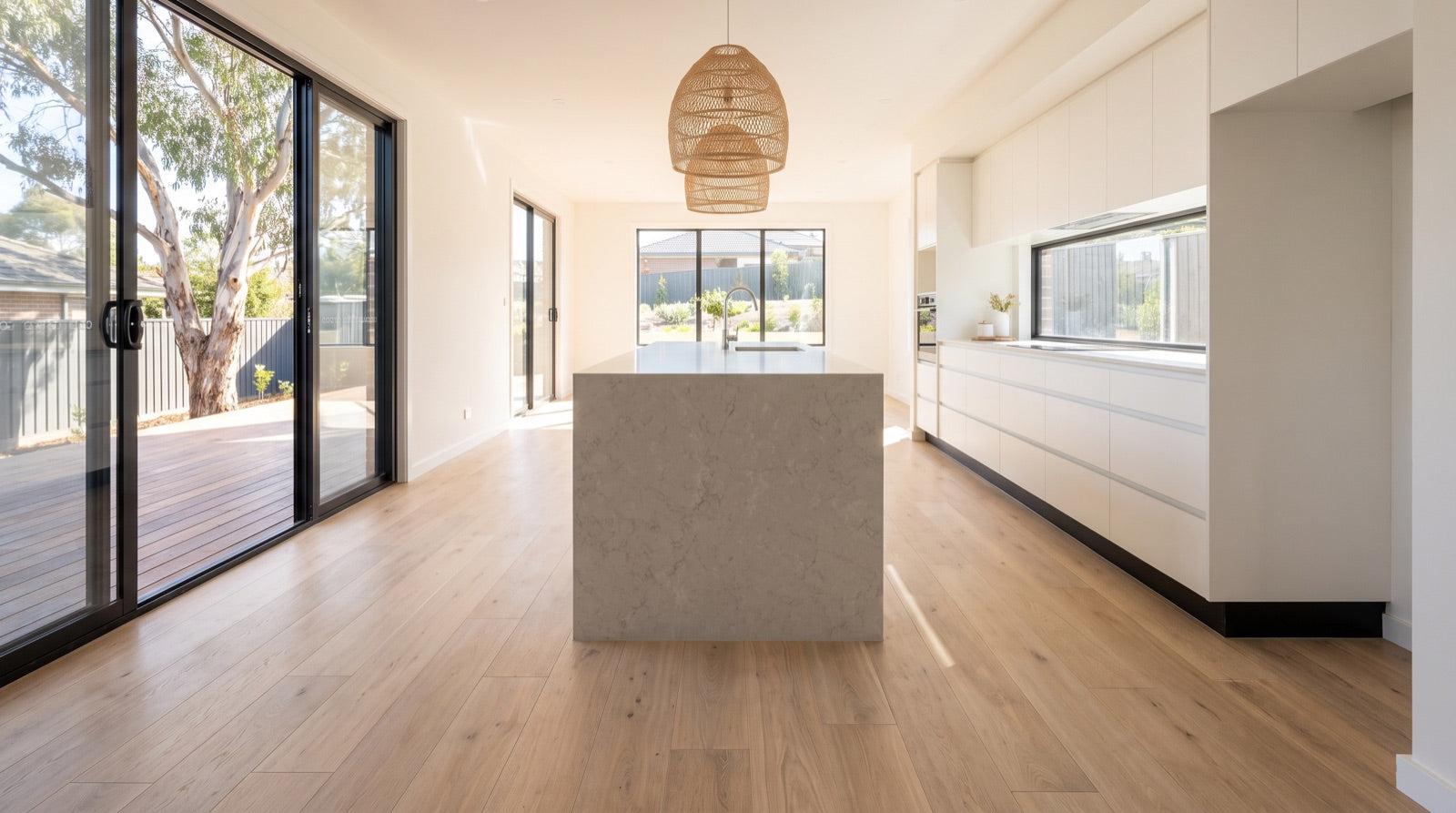 Australian kitchen with a stone island and pale oak floating floorboards running up to the cabinet kickboard line