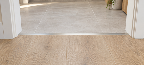 Illustration of a slim transition strip joining a timber-look floor and tiles in a doorway.