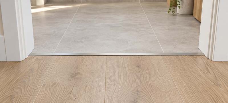 Illustration of a slim transition strip joining a timber-look floor and tiles in a doorway.