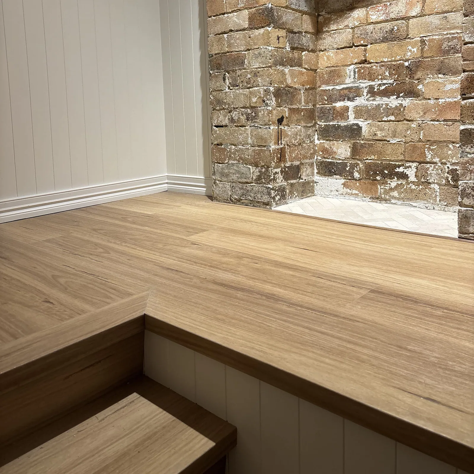 Coastal Blackbutt 6.5mm hybrid flooring beside a brick fireplace