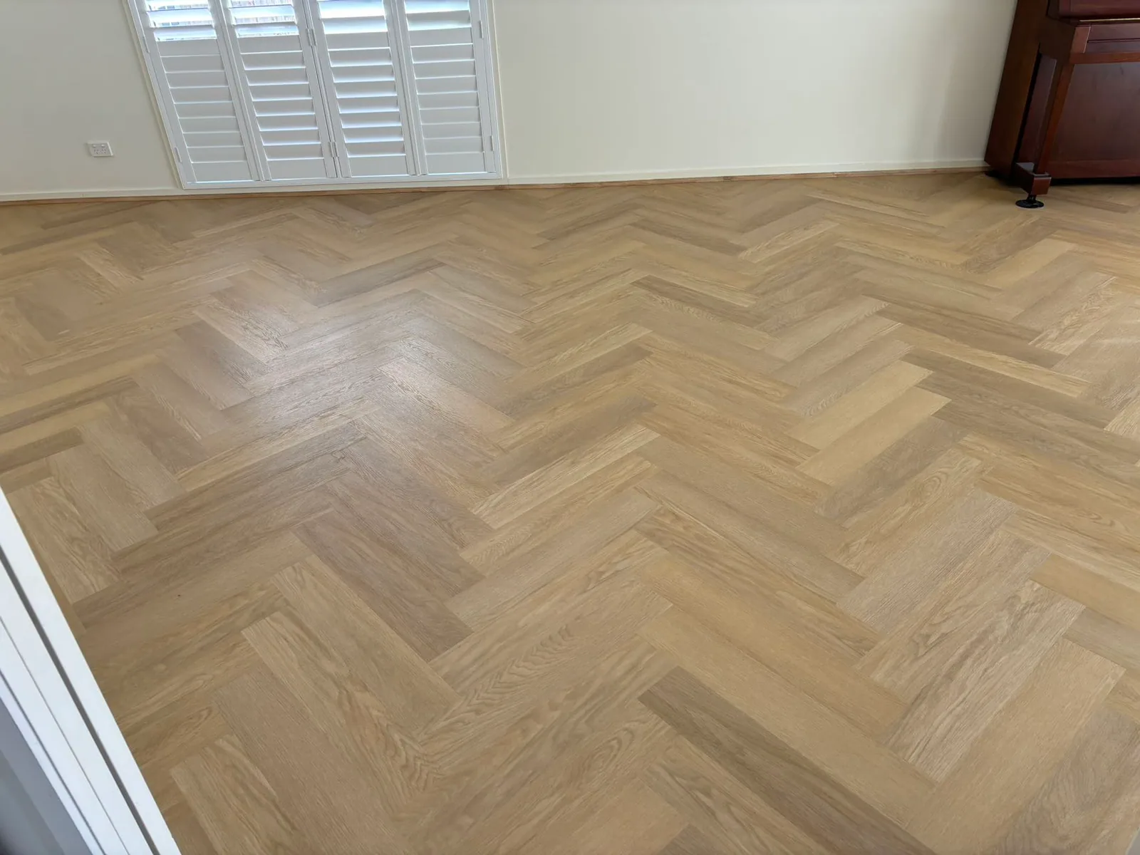 French Oak 9.5mm herringbone hybrid flooring across a room with white shutters