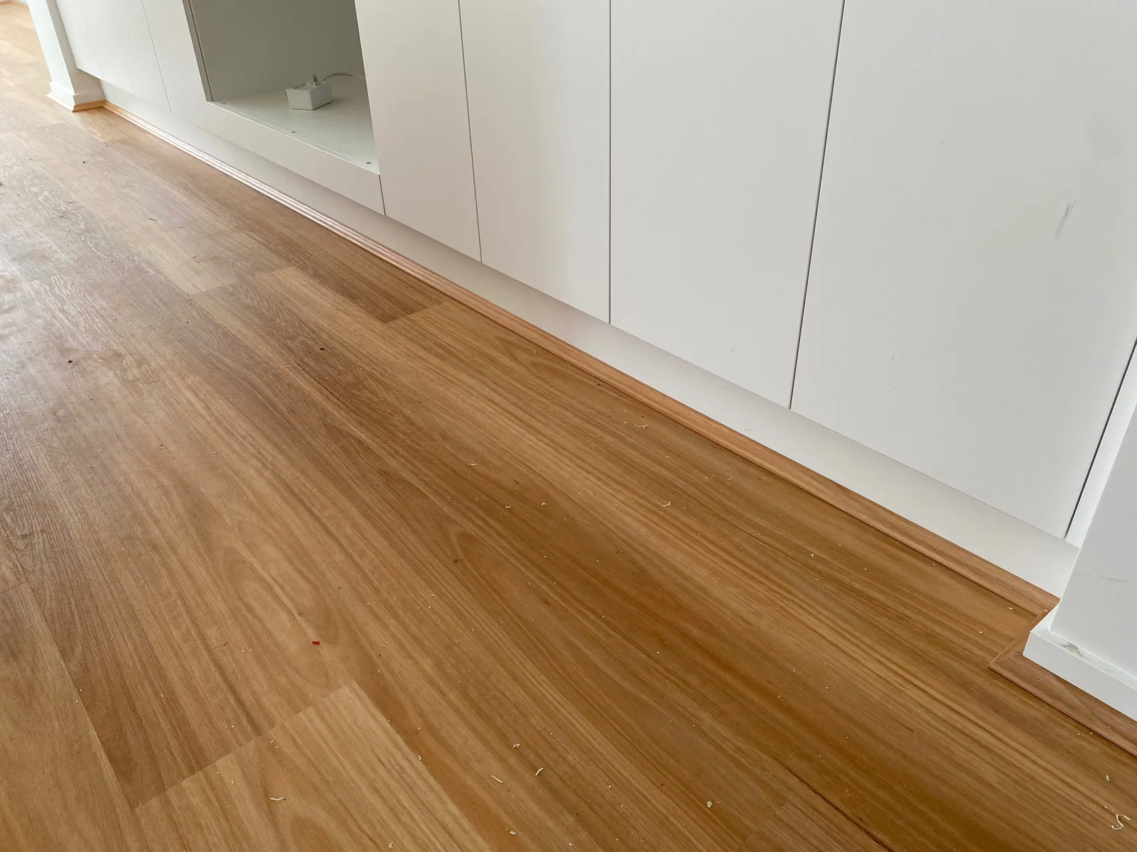 Natural Blackbutt 9.5mm hybrid flooring beside white kitchen cupboards