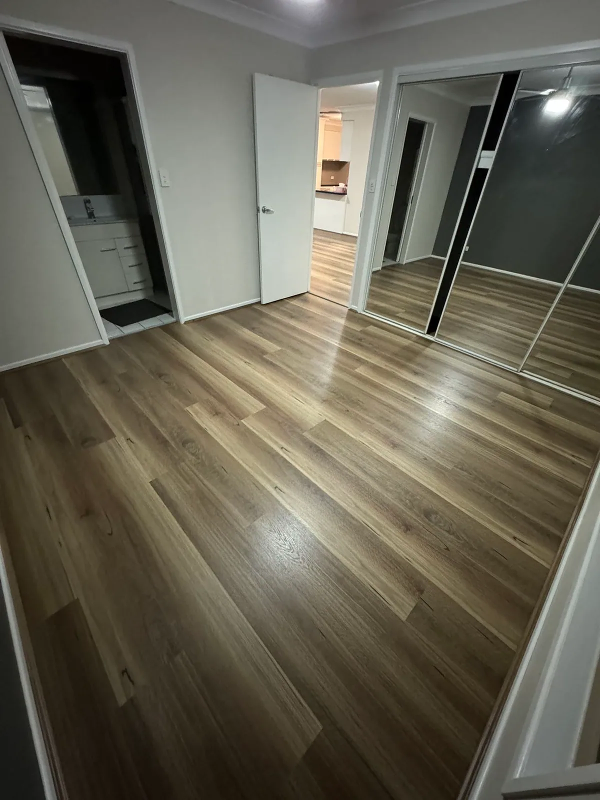 Natural Spotted Gum 9.5mm hybrid flooring in an empty room with mirrored cupboards