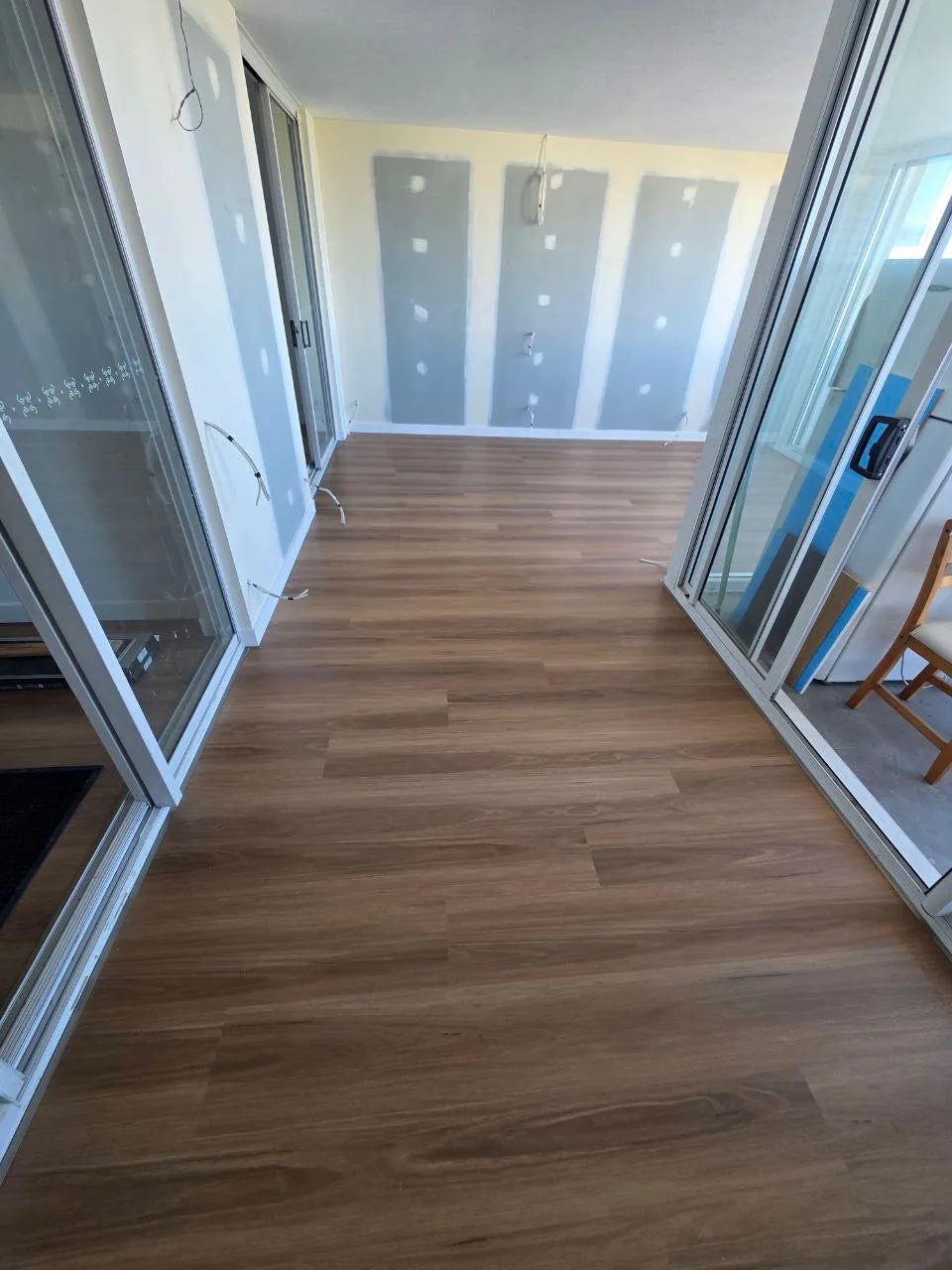 New England Blackbutt 9.5mm hybrid flooring in a hallway with mirrored wardrobes during installation