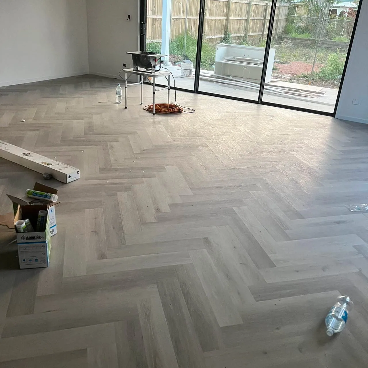 Snow Grey 9.5mm herringbone hybrid flooring in a room with sliding garden doors