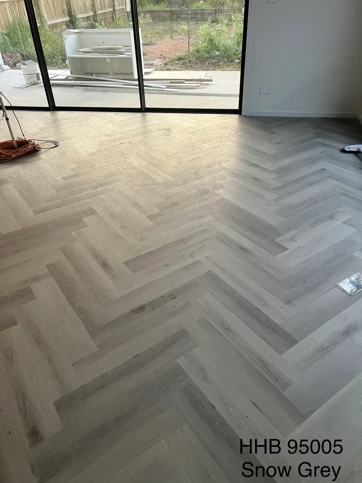 Snow Grey 9.5mm herringbone hybrid flooring across a room toward garden doors